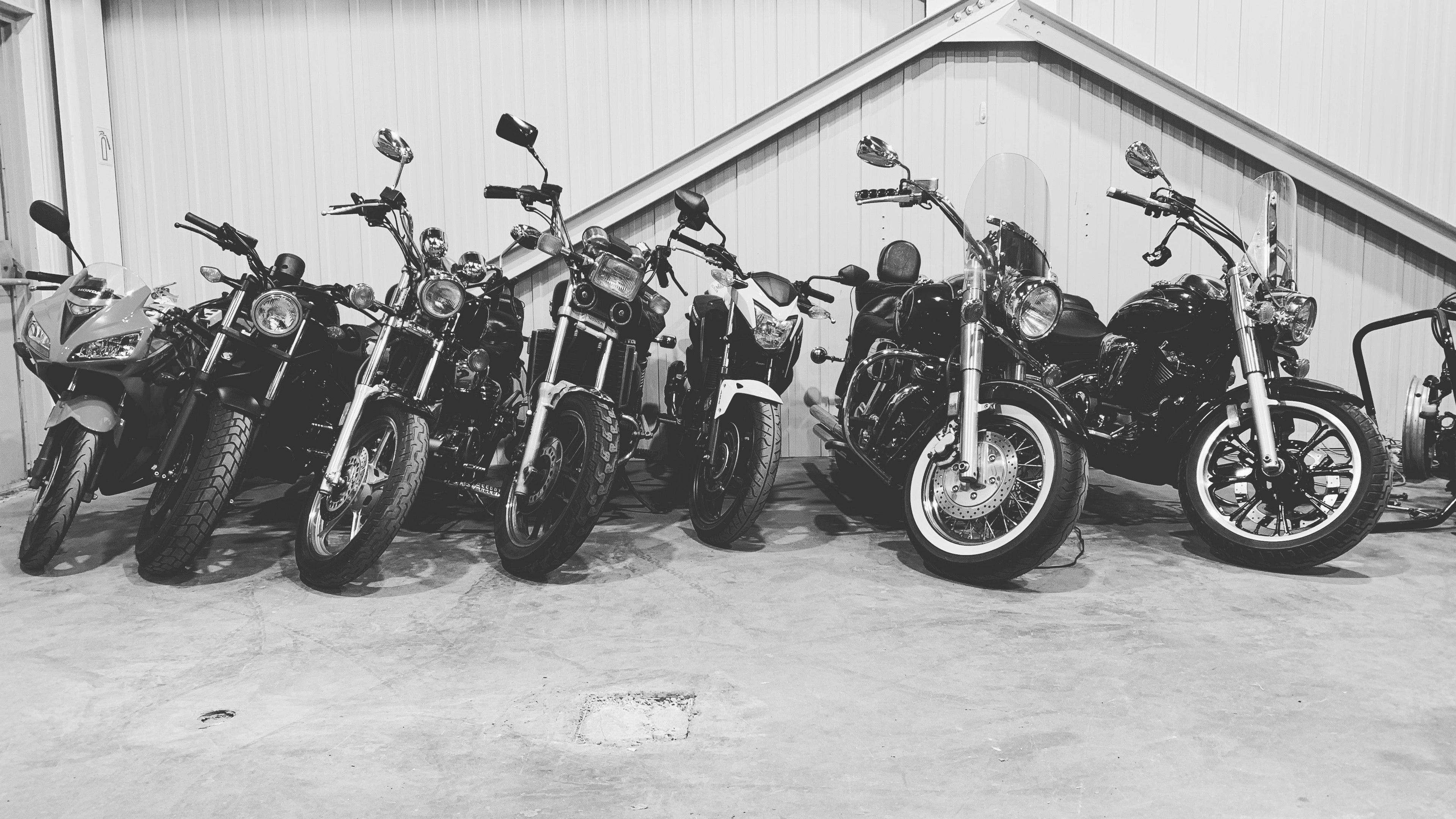 Row of motorcycles parked inside a building with a white interior.